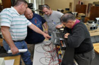 Students working on equipment using their hands and tools