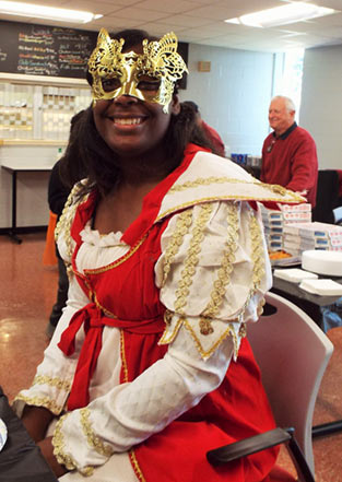 A student smiling at the camera while wearing a Halloween costume and mask